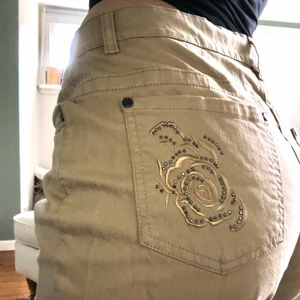 Byxor med rhinestones! - Så coola beiga byxor i nyskick! Så fina rosor på bakfickorna med små stenar/rhinestones. Säljer då de helt enkelt inte kommer till användning. Står storlek 42 på lappen men de sitter såhär på mig som brukar ha 38. Dem är perfekta om man vill ha en mer baggy look! 180 eller buda högre! Jag är 163 cm ☺️☺️