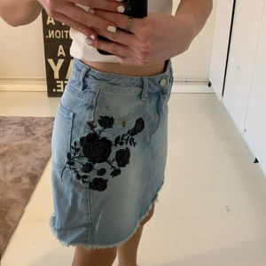 Jeanskjol i strl 36 - Snygg jeanskjol från NA-KD i storlek 36. Använd några gånger under förra sommaren. Har en stor svart ros insydd på högersidan men det är snyggt och gör kjolen annorlunda! 75kr 