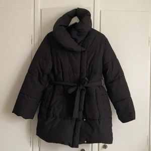 Svart jacka med hög krage - Sparsamt använd jacka med dubbelknäppning, hög krage och avtagbart band i midjan. Storleken upplevs som en small snarare än xs, alternativt en oversize fit. 