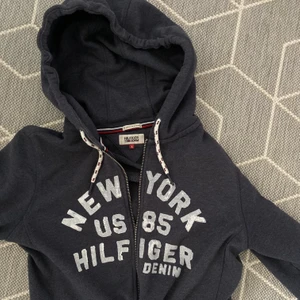 Tommy hilfiger blå hoodie - Så fin marinblå Tommy hilfiger hoodie. Den är i jättebra skick och använd sparsamt. Den är i storlek L och därför ger den en assnygg oversized fit. Så fin över linnen. Kan skicka fler bilder😇