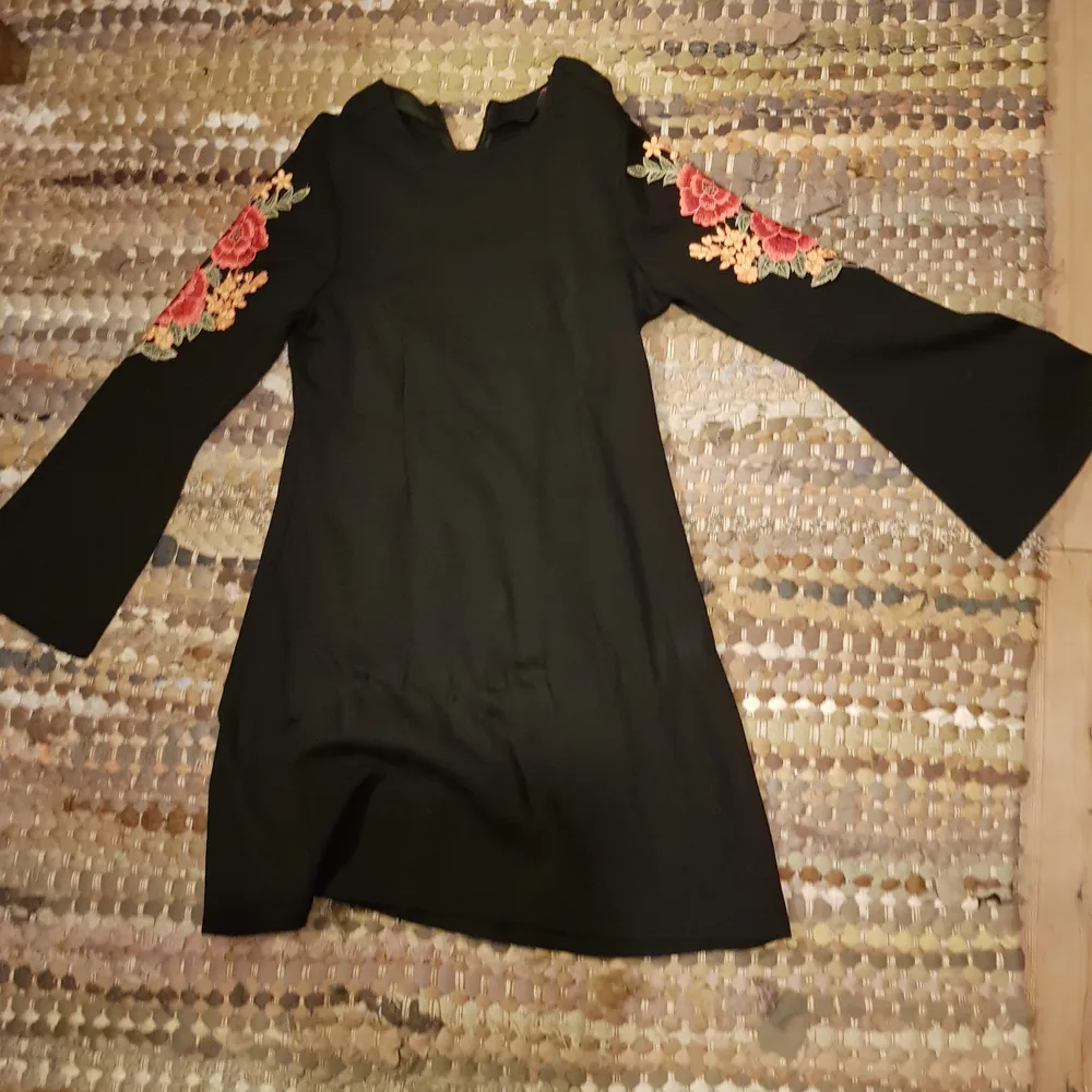 En supersöt svart klänning från indiska, med rosor och utsvängda armar. Går till mitten av låret. Använd 3 gånger. Klänningar.