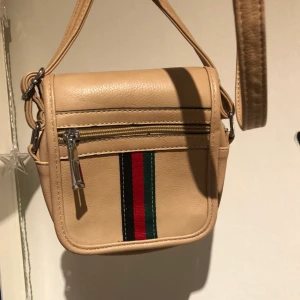 beige axelväska - fin axelväska i fejkläder. bandet är ganska långt och justerbart. 