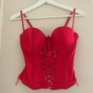 Röd korsett - Snygg röd korsett med fina detaljer och snören❤️ Den är justerbar i ryggen och är storlek 75C men skulle mer säga 75B. 100kr+frakt eller högstbjudande:)