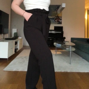 Bikbok Högmidjade Kostymbyxor - Svarta kostymbyxor från BikBok i strl XS. Jag är ganska kort (158) med bred över höfterna och brukar ha 36/38 i byxor. På mig är de precis på gränsen till lite små och och lite långa. Sparsamt använda. Priset är exklusive frakt. 