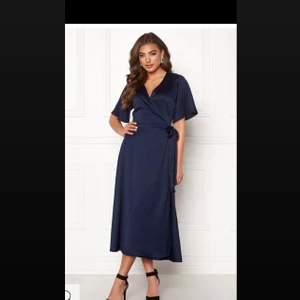 Storlek 40/42 Pris kan diskuteras  - * Storlek 40/42 * Färg: Dark blue * Material: 100% polyester. * Tvättråd: 40° skontvätt. * Festlig wrap-klänning i en lyxig kvalitét * Tillverkad i en vacker stum kvalitét med fin lyster. * Ej avtagbart knytband i midjan. Anbänd bara en gång, köpte för 600 kr ock säljer för 350kr. Pris kan diskuteras.