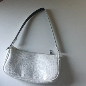 Axelväska  - Axelväska i vit läder-imitation med dragkedja, inga innerfack. Använd 2ggr.