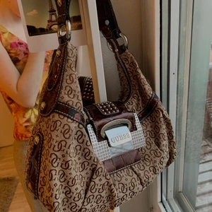 Guess väska - Liten väska från guess i brunt. Detaljer som brunt läder, små diamanter etc.   VÄSKAN ÄR I STHLM VILKET GÖR ATT JAG INTE KAN POSTA DEN ATM 