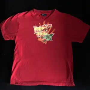 Röd tshirt med färgglatt tryck och v-ringning. Slitage i trycket förekommer men annars bra skick. 