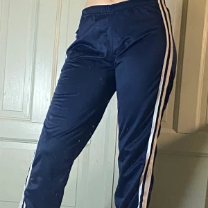 Tränings/mjukis byxor  - Mörkblå träningsbyxor från asics med vita ränder längs benen. Strlk S