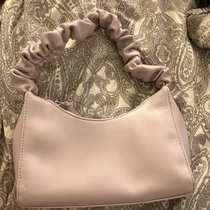 Lila väska - Säljer denna lila väska från Gina tricot den är lite smutsig på under sidan men går säkert att få bort. Max andvänd 10 gånger och väldigt fin kvalite 