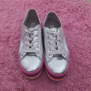 Vill du ha lite Rainbow på dina skor? Nu kan du! Här finns ett par skor med regnbågs färg samt silver som lätt kan göra vilket outfit som helst coolare. Skorna är i bra skick och söker en ny ägare. 