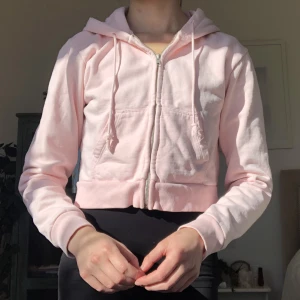 Brandy Melville crystal hoodie - Pastellrosa croppad munkjacka/huvtröja ifrån Brandy Melville! I gott skick☺️ Min läng och så står i min profil!    Super soft cropped fleece-lined hoodie with a zip-up front and side pockets. Fabrics: 75% cotton, 25% polyester