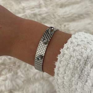 Silvrigt armband m stenar - Säljer detta fina silvriga ”hårda” armbandet med stenar på. Ska passa alla handleder då de både går att töja ut och göra det mindre. Aldrig använt, helt nyskick. Säljer för 500 kr. Köparen står för frakten!