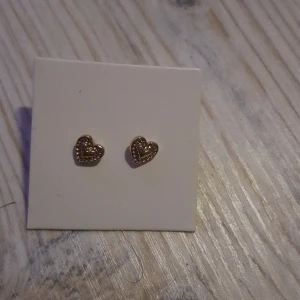 Hel nya guldfärgade örhängen  -  Helt nya gulfärgade örhängen, hjärtformade 0,5 cm bredd. Aldrig använda!