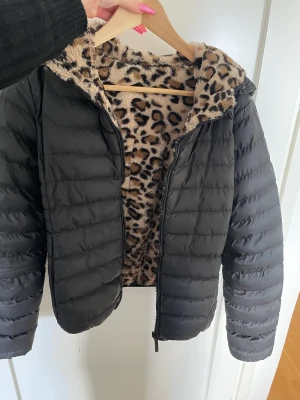 Jacka - Skön och snygg jacka med luva. Man kan ha den antingen med dun sidan utåt eller så kan man vränga den så leopard sidan är utåt