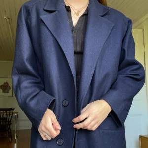 En oversized marinblå kappa i storlek 42 från Dahlens Modell - Svensk tillverkning. Snygg oversized modell på mig som har storlek 36 och är 175cm. Sparsamt använd i fint skick. 80% ull. 