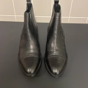 Svarta ormskinnsmönstade boots - Svarta ormskinnsmönstade boots i äkta läder från Bianco. Aldrig använda. Nypris: 1500 kr. 