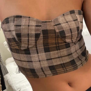 Rutig bandeau topp - Supersnygg crop top i bruna nyanser med liten dragkedja på sidan för att smidigt få på sig den.