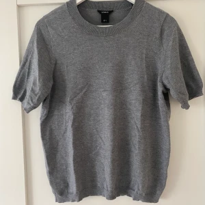 Grå stickad t-shirt lindex - Grå stickad t-shirt ifrån Lindex. Stl S. Fint skick bortsett från ett litet hål vid lappen i nacken! Hålet sitter dock på ett sådant ställe att det enkelt skulle gå att laga med några stygn. Köparen står för frakten.