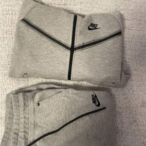 Detta är ett grått Nike tech fleece set från TJEJ avdelningen. Detta betyder att zip hoodien är kortare och samma med byxorna. Zip hoodien är mer använd, den är lite sliten vid handlederna men byxorna är helt i skick. Köpt från JD sport för 2300kr.