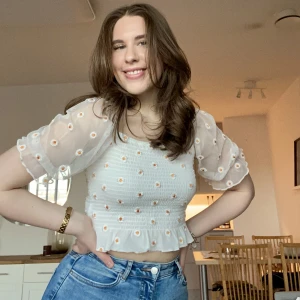 Gullig topp strl M - Supersöt vit topp från BikBok med prästkragar på i storlek M. Använd endast ett fåtal gånger så den är i mycket fint skick. Har meshtyg på ärmarna och blommorna är broderade. Resår i midjan så den är stretchig. Så fin till våren! 🌟🌸