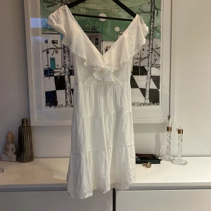 Klänning - Vit fin klänning. Använd en gång. Köpte för att kanske ha den på studenten för några år sen, så har tyvärr därför glömt bort vart jag köpte den. Finns en liten skada vid axeln, syns inte när klänningen är på.