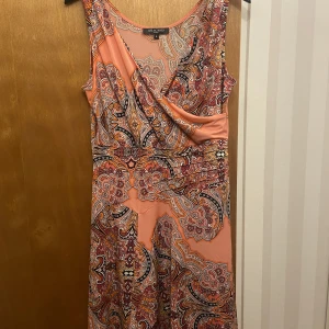 Mönstrad klänning - Mönstrad persikofärgad klänning, slutar strax ovanför knäna. 