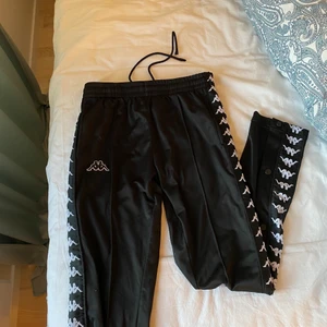 Kappa byxor  - Säljer mina svarta kappa byxor med knappar på sidorna då dom inte kommer till användning längre. Skulle säga att skicket är mycket bra. Inga fläckar eller slitningar. Sitter bra på mig som är 164cm. Nypris när jag köpte dom var 599kr. ✨Säljer för 100kr + frakt✨