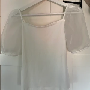 Vit blus Gina tricot - En söt top från Gina som är väldigt stretchig men lite genomskinlig. Knappt använd. Dma för bilder eller frågor.