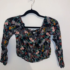 Topp med bara axlar - Blommig topp som är tänkt att sitta endast på axlarna så att de blir en rak linje. Storlek 32. Orginalpris 149kr. Tunt skönt material. Om man vill kan jag fixa bilder på hur den sitter på.