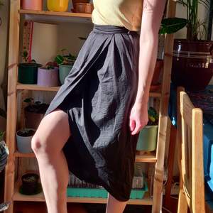 Fin kjol med dramatisk slits framtill, finns underkjol vid lämplig längd. Materialet är fint och lite sidenaktigt.