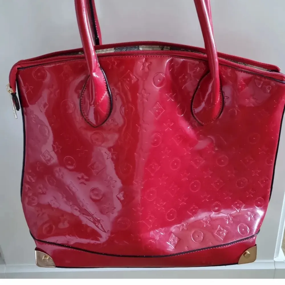 Röd väska med coolt mönster på. Även guldfärgade detaljer. Väskor.