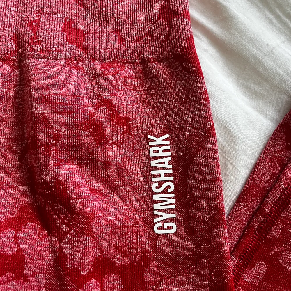 Gymshark tights i röd färg med kamouflage-mönster, de är aldrig använda och helt nya. Lappen sitter inte kvar däremot. Storlek small. Köparen står för frakt!. Jeans & Byxor.