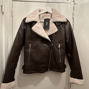 Skinnjacka - Helt ny skinnjacka i mörkbrunt med mudd. Stl XS. Jätte fin och åtsittande!