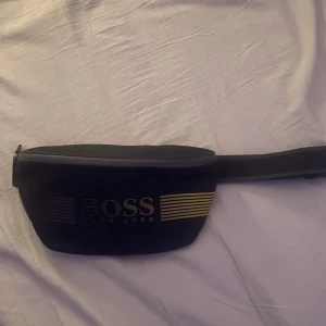 Hugo boss midjeväska - Säljer nu min Hugo boss väska för jag använder den inte längre Den är i bra skick knappt använd bara ett fåtal gånger. Perfekt för sommaren eller utomlandsresa