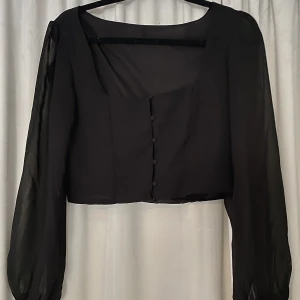 Svart blus - En fin svart blus med knappar fram, fina armar med mer genomskinligt tyg.