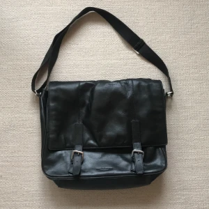 Skinnväska tiger of sweden - Inköpt second hand, använt skick. Rymlig och med justerbart axelband. Stort och litet fack inuti samt ett fack på baksidan.  Lite sliten på vissa ställen, kan skicka fler bilder vid önskemål. 