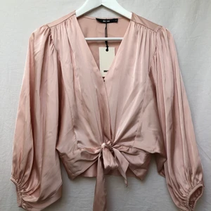 Rosa blus  - Helt oanvänd rosa blus som man knyter i midjan, man kan knäppa den högt eller lågt vid bysten.