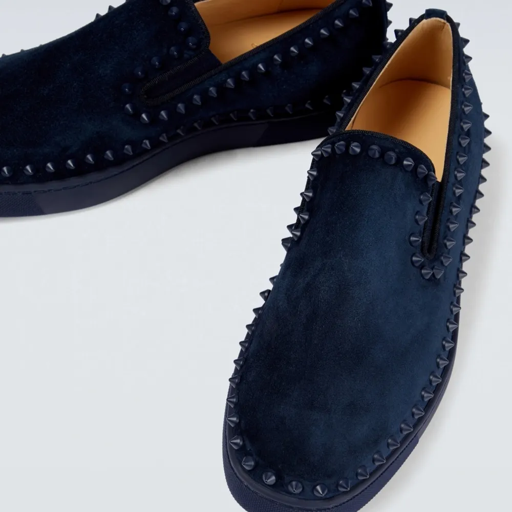 Low-top suede slip-on sneakers in navy. Signature stud detailing throughout.  · Elasticized gussets at vamp · Buffed leather lining · Signature red rubber sole  Supplier color: Marine/Marine mat Upper: leather. Sole: rubber.  Made in Italy.     . Skor.