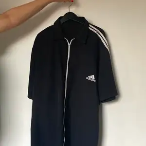 Adidas skjorta i bra skick med dragkedja istället för knappar, den är i idrottsmatreal och funkar till träningen och vardagen.