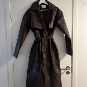 Trenchcoat PU - Säljer min oversized trenchcoat i PU. Svin snygg mörkbrun färg. Aldrig använd. Frakten tillkommer på 100kr