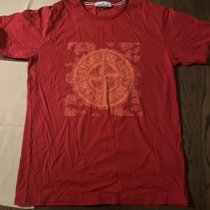 Stone island T-shirt  - En röd Stone island med ”spray” motiv i storlek L. Jag har fått den i födelsedagspresent i somras men den är för stor för mig. Använd 3-4 gånger alltså i nyskick! Nypris för Stone island T-shirt brukar ligga på 1200kr och uppåt. 