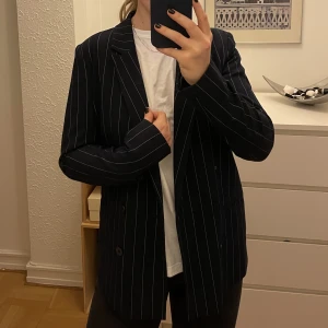 Marinblå kavaj med cigarettränder - Skitsnygg kavaj/blazer köpt från Pimkie i Frankrike. Fickorna är inte uppsprättade, knapparna är svarta. Liten i storleken, skulle rekommendera för någon mellan 34/36!