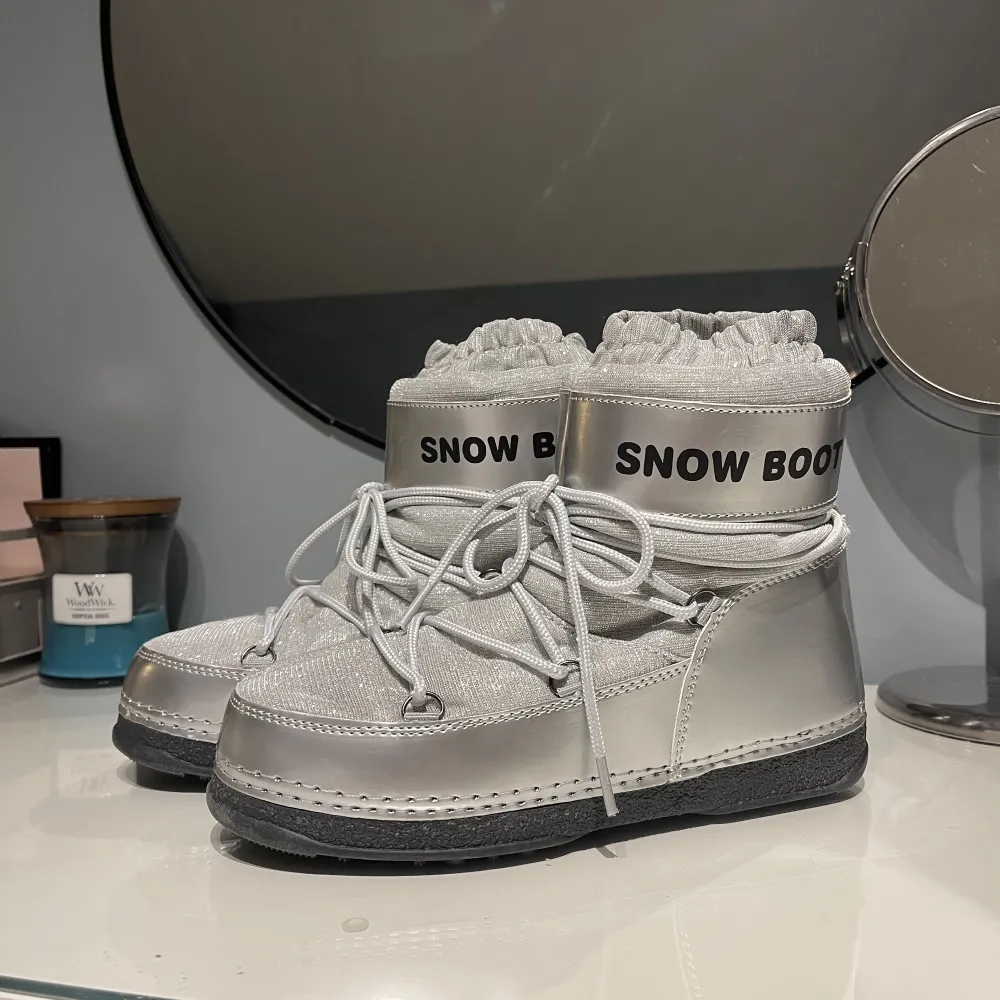 Säljer ett par helt nya och oanvända snowboots i en silver och glittrig design. Skorna är gjorda med en mugg högst upp för att förhindra att snö kommer in i skon. Är i storlek 38/39 men passar nog mer en 37/38 då de är något mindre i storlek. 🤍❄️. Skor.
