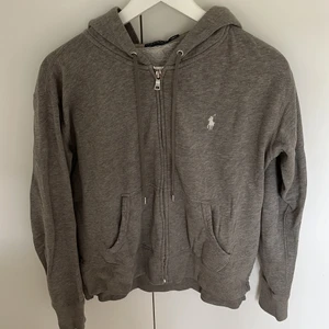 Huvtröja - Så fin tröja med dragkedja ifrån Ralph Lauren. Den är grå med fickor på sidorna samt en luva. Jätteskön och i mycket fint skick!