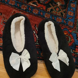 Mjuka Tofflor - Mjuka svarta tofflor med vit rosett. Sammmetsliknande, med vit  teddy inuti. Ca stl.36-37. Använda, välvårdade. Frakt tillkommer.