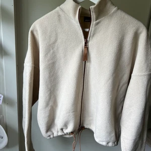 Beige stilig fleece  - mycket snygg fleece som går att matcha med allt.  Tröjan är i fint skick. Anpassa själv i resor banden längst ner på tröjan hur tajt du vill ha den.  