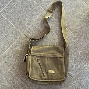 Axelremsväska i tyg, tygväska  - Axelremsväska i tyg med justerbart band i en grön beige nyans. Unisex i märket: Simon Vouge Leather. Kan även posta om det önskas🌼