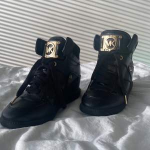 Ett par fantastiska michael kors sneakers som är i fantastisk skick dem har svart som basfärg och rosegulda detaljer som verkligen ger skon en upplysning.