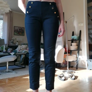 Holly & white chinos - Marinblå chinos-aktiga byxor. Guldiga knappar vid fickorna. Knäppning i sidan, saknas en knapp på insidan för att säkra att dragkedjan håller sig uppe (lätt att sy till själv). Från Holly & White by lindex